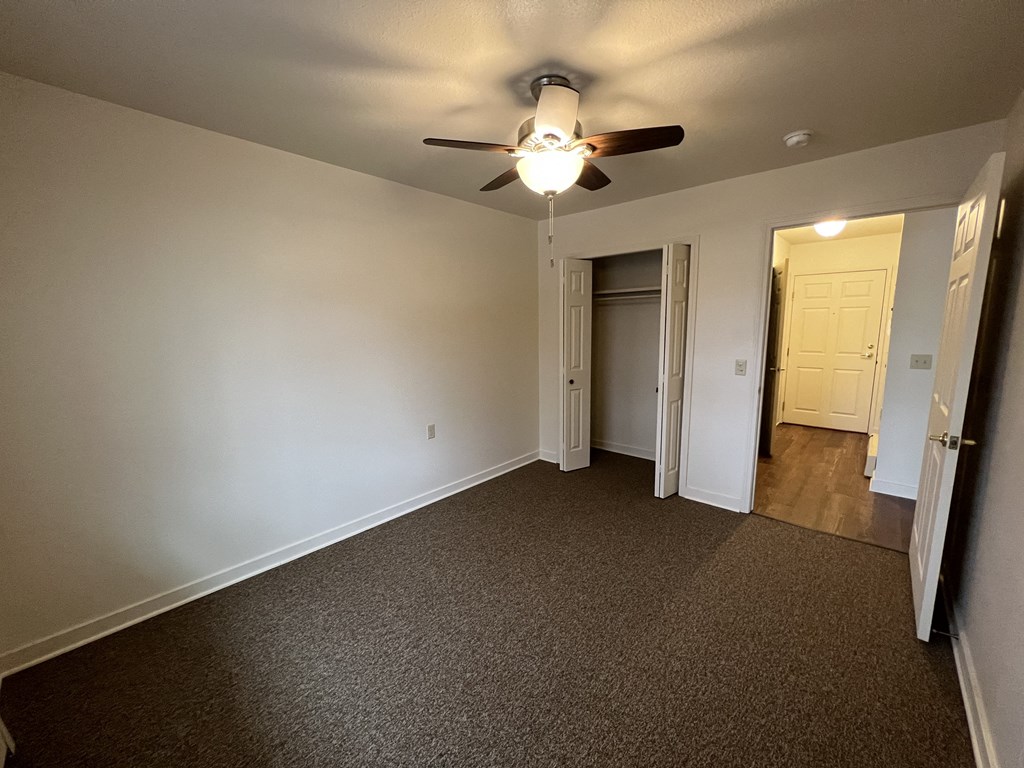 a bedroom with a ceiling fan and a door to a bathroom