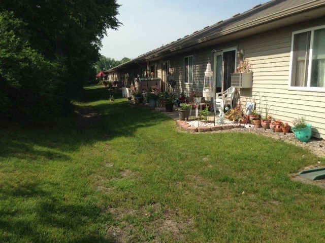a view down the side of a house with a green lawn and potted plants