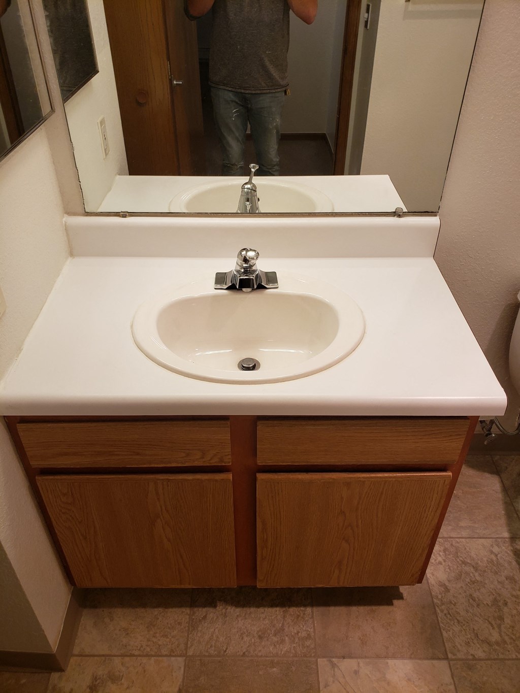 a sink in a bathroom with a person taking a picture in the mirror