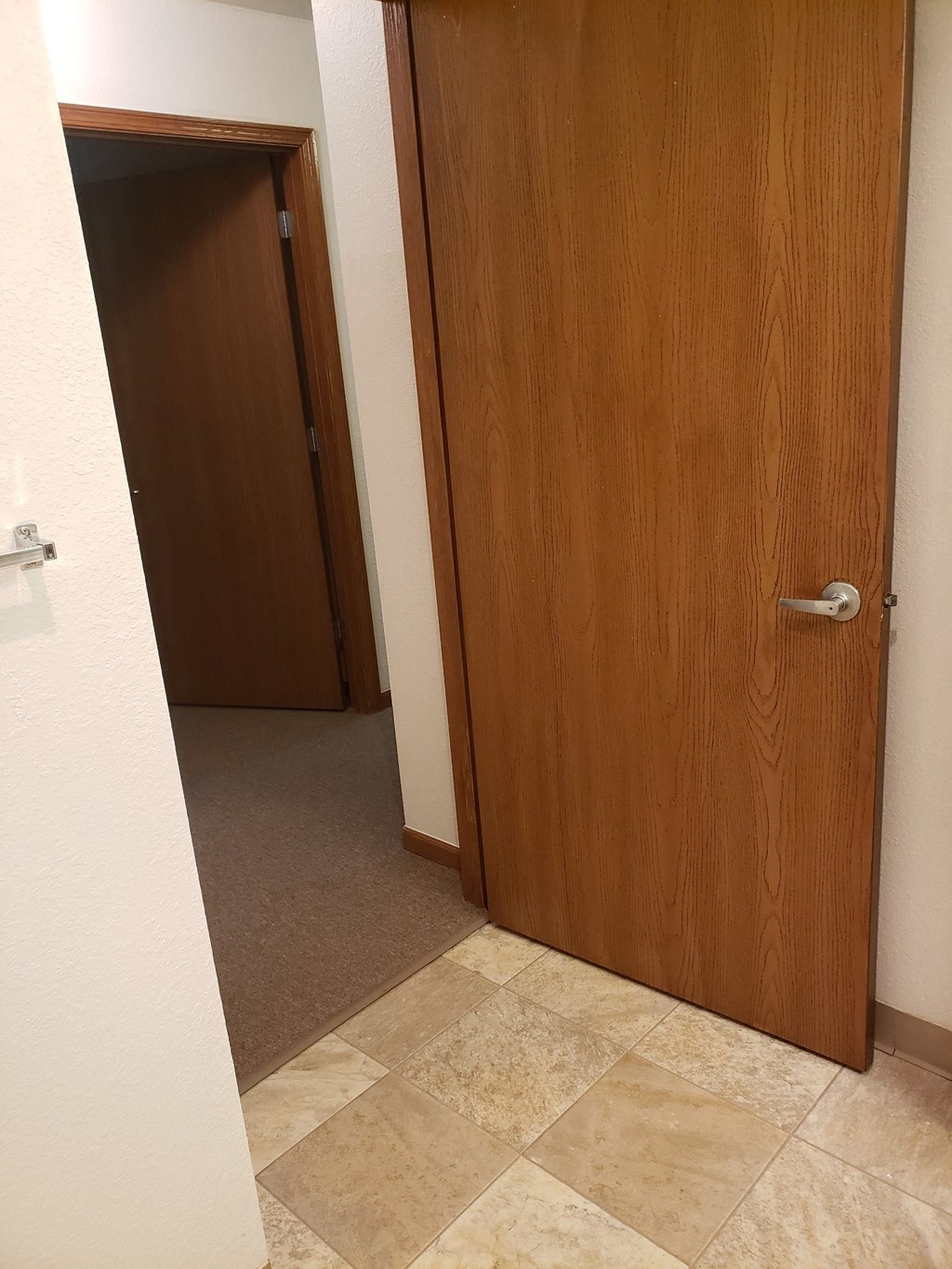 an open door leading to a hallway with a door to another room in the background