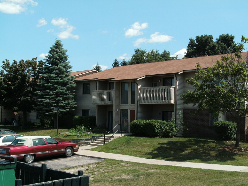 an apartment building with a red car parked in front of it