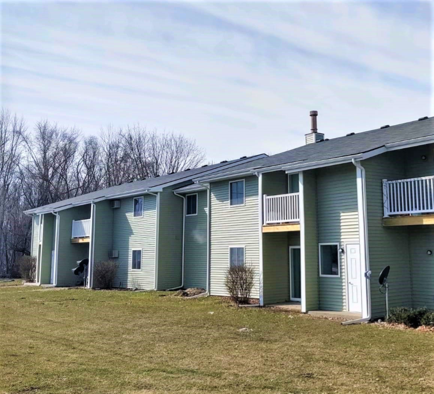 a green and white apartment building with a grass field