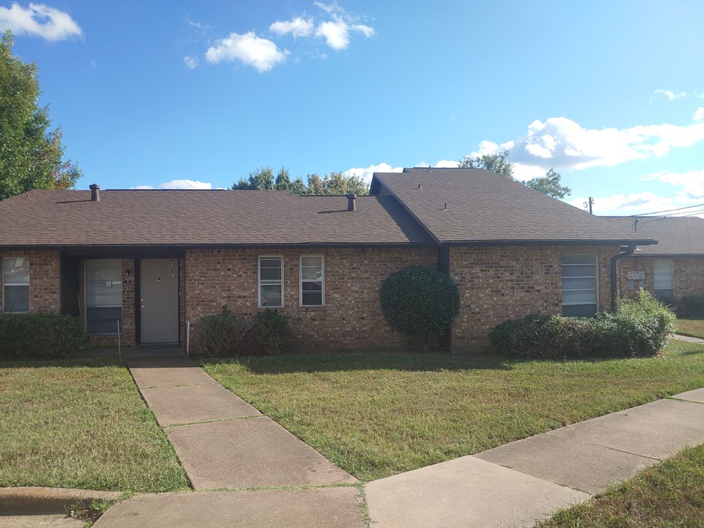 a brick house with a sidewalk and grass