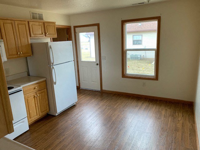 an empty kitchen with a refrigerator and a window