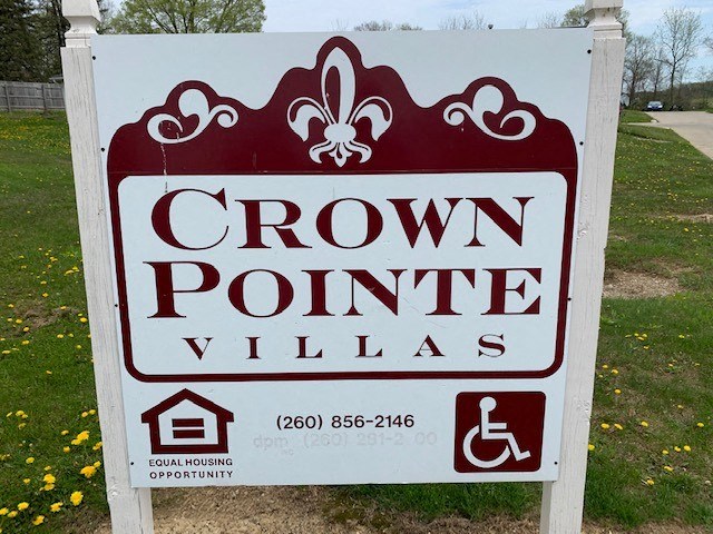 a sign that says crown point village in front of a field