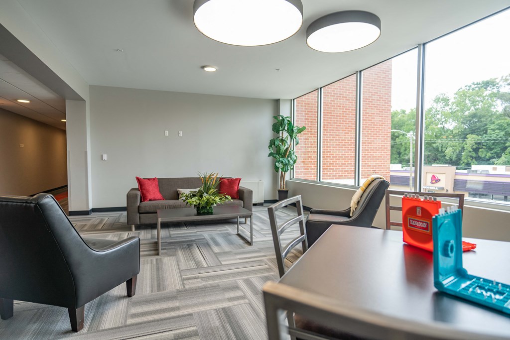 a room with a table and chairs and a couch in front of a window