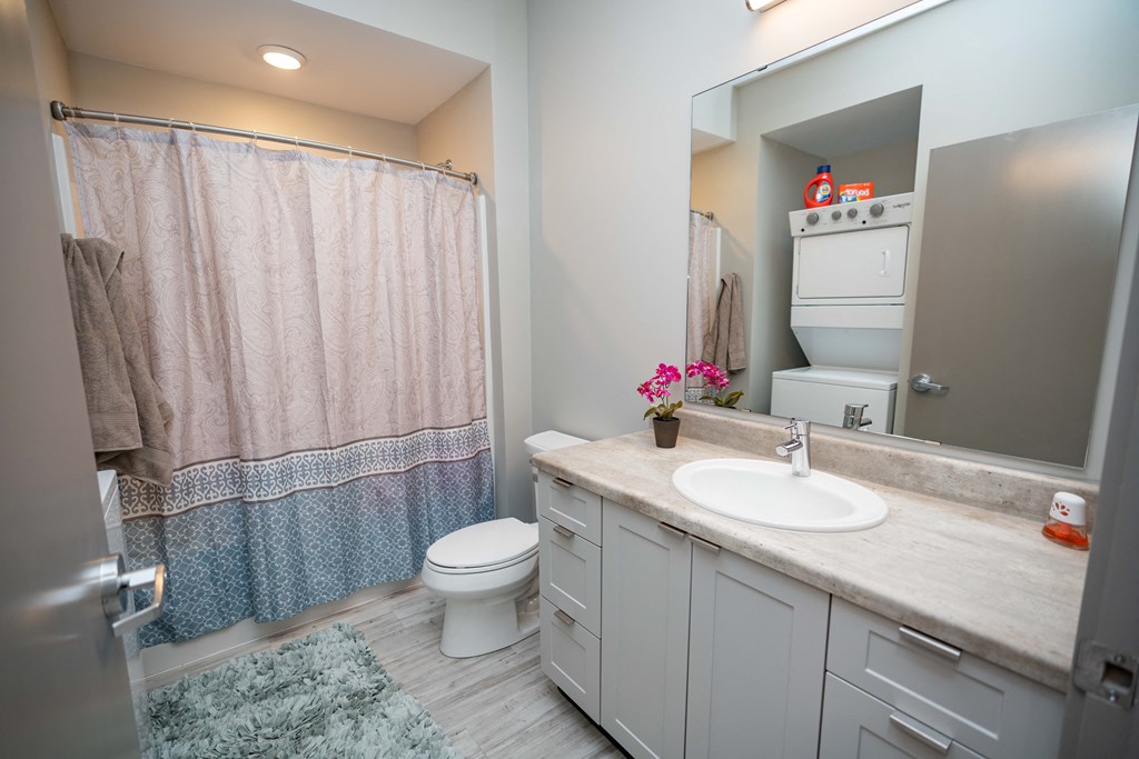 a bathroom with gray cabinets and a blue and white shower curtain