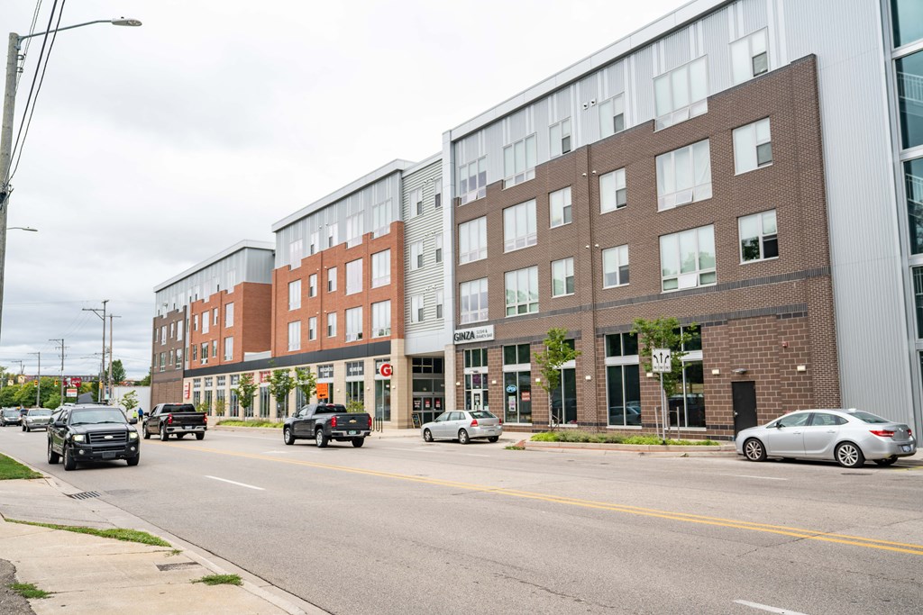 a large brick building with many windows and cars parked on the side of the road