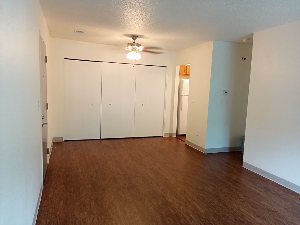 an empty living room with white walls and a ceiling fan