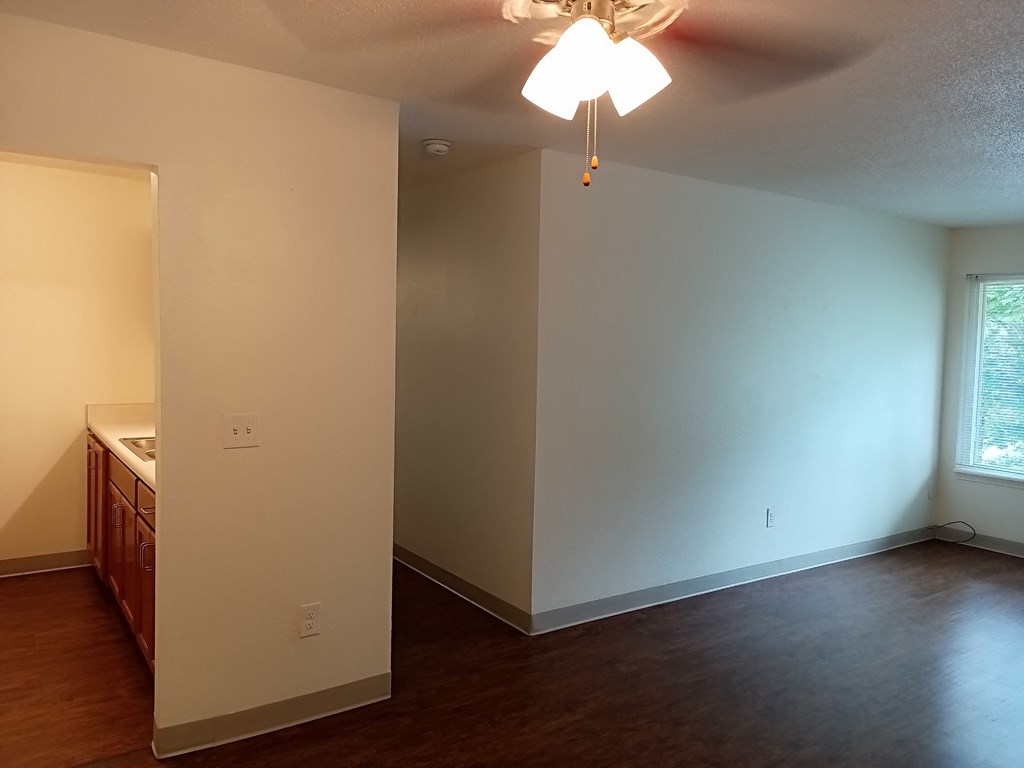 an empty living room with white walls and a ceiling fan