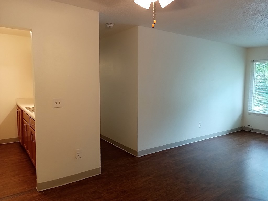 an empty living room with a wood floor and white walls
