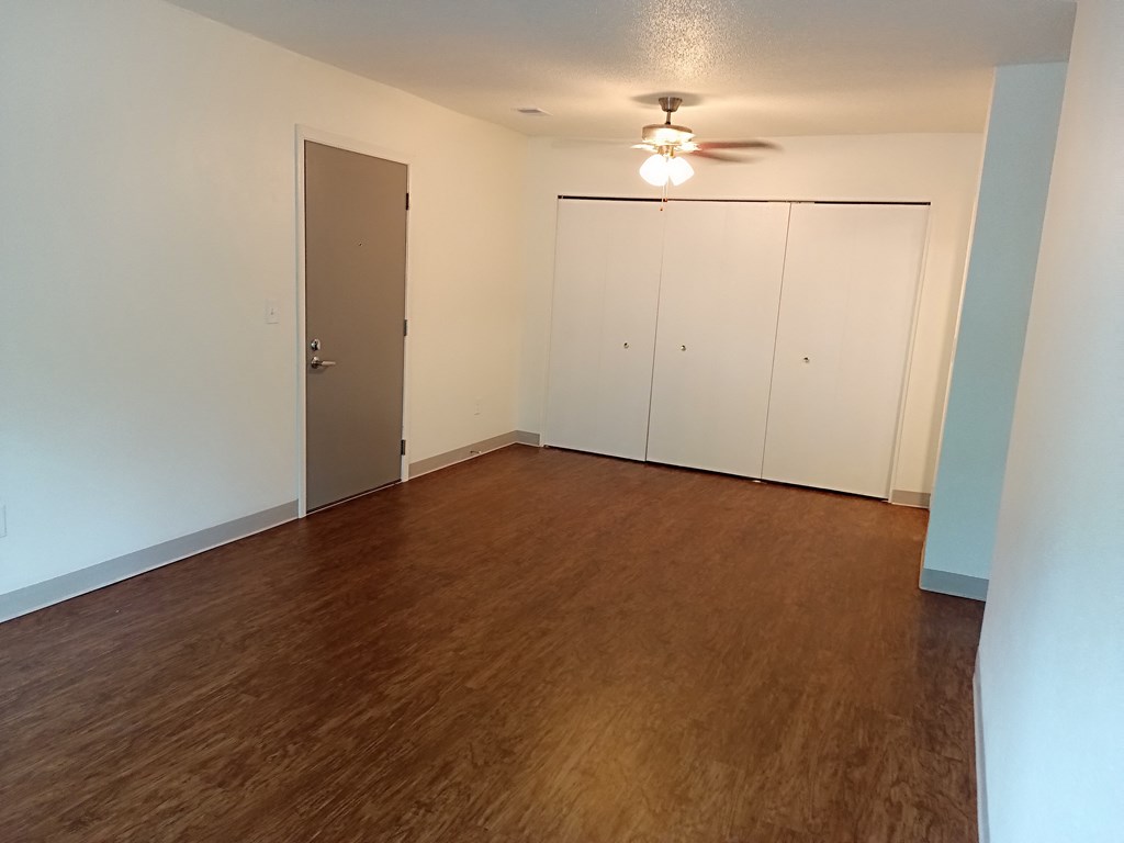 an empty living room with wood flooring and a ceiling fan