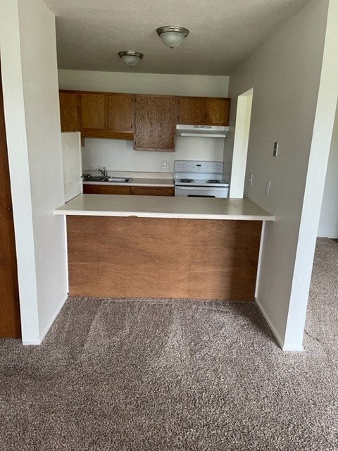 an empty kitchen with wood cabinets and a white counter top