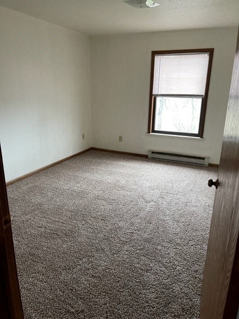 an empty room with a window and white carpet