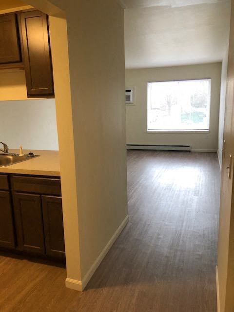 an empty kitchen with wood floors and a window