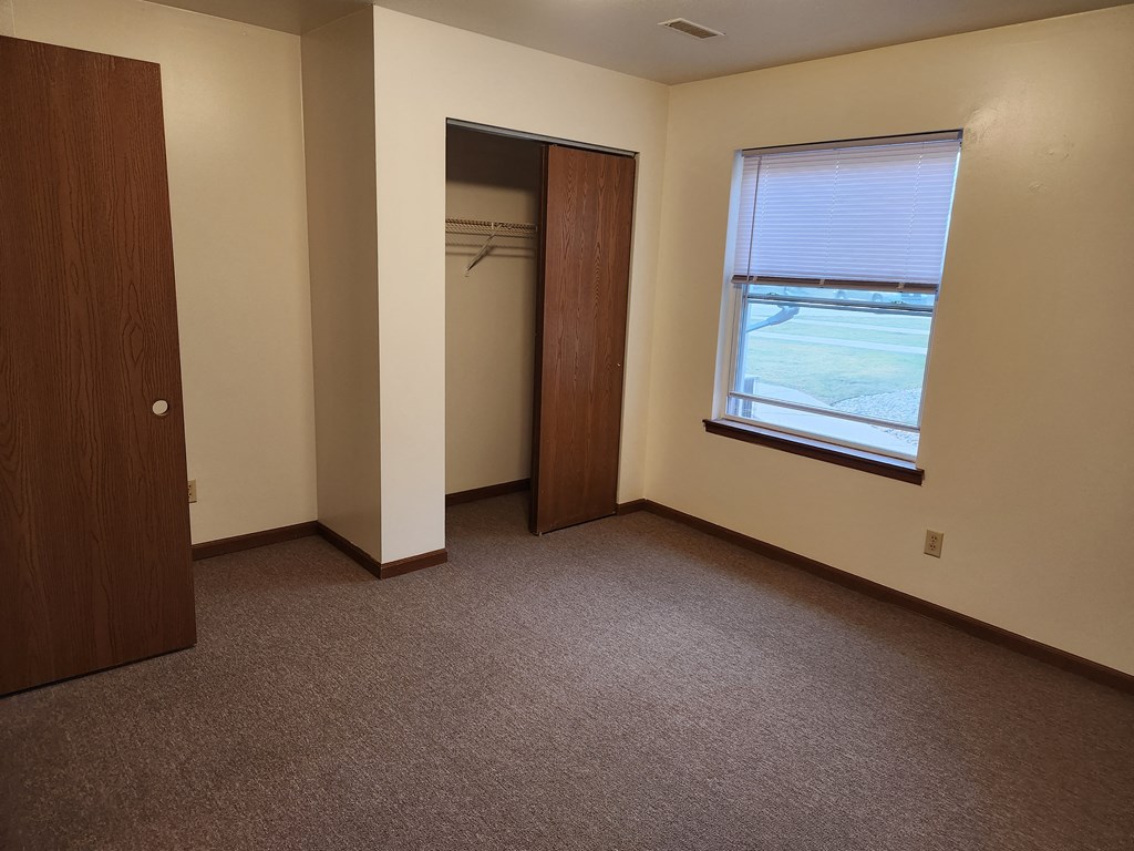 an empty room with a window and a closet