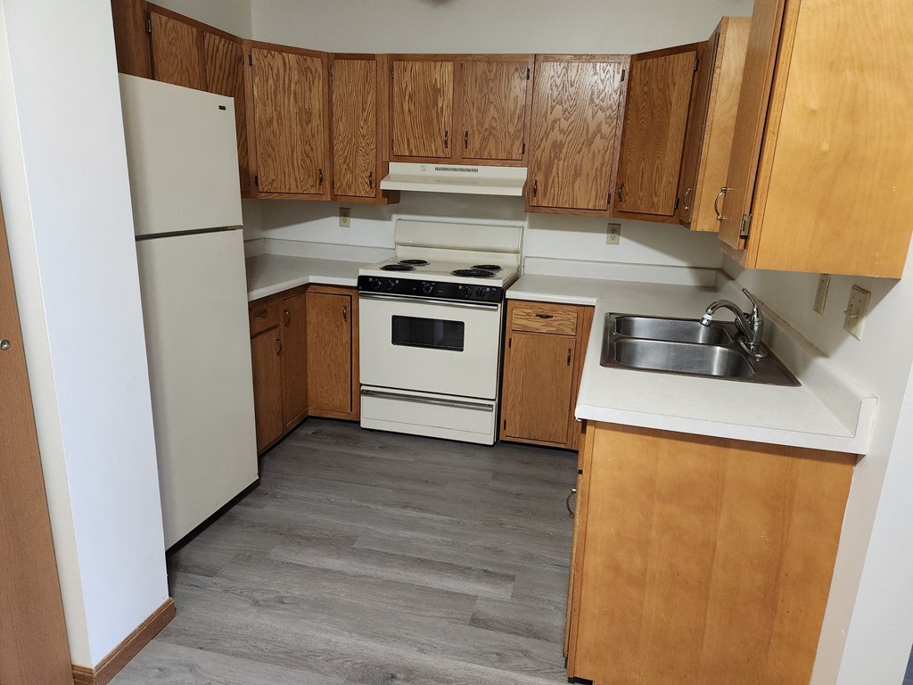 an empty kitchen with white appliances and wooden cabinets