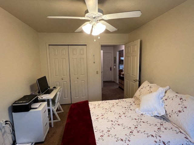 a bedroom with a bed a desk and a ceiling fan