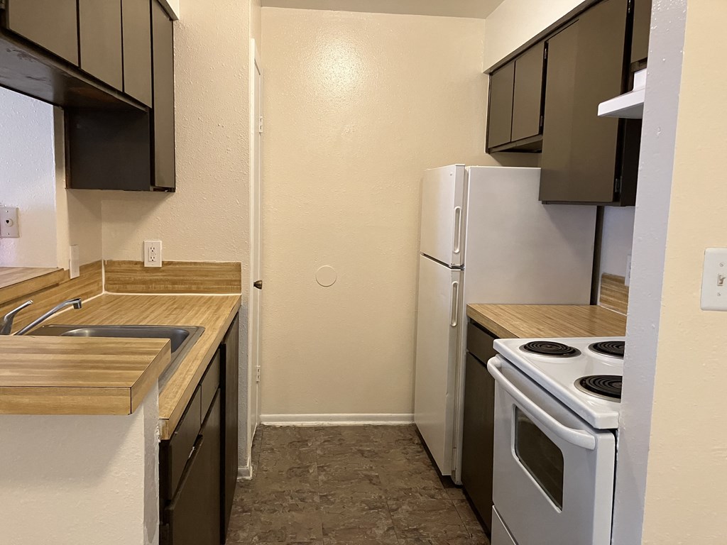 an empty kitchen with a stove refrigerator and sink