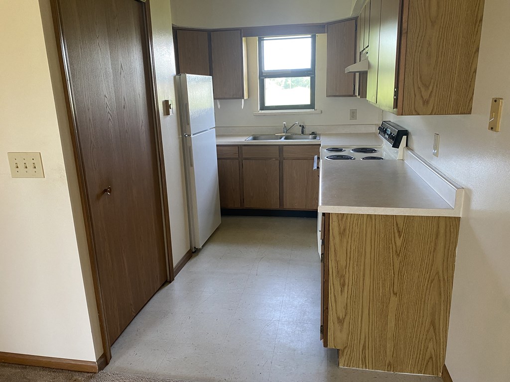 an empty kitchen with wooden cabinets and a white counter top