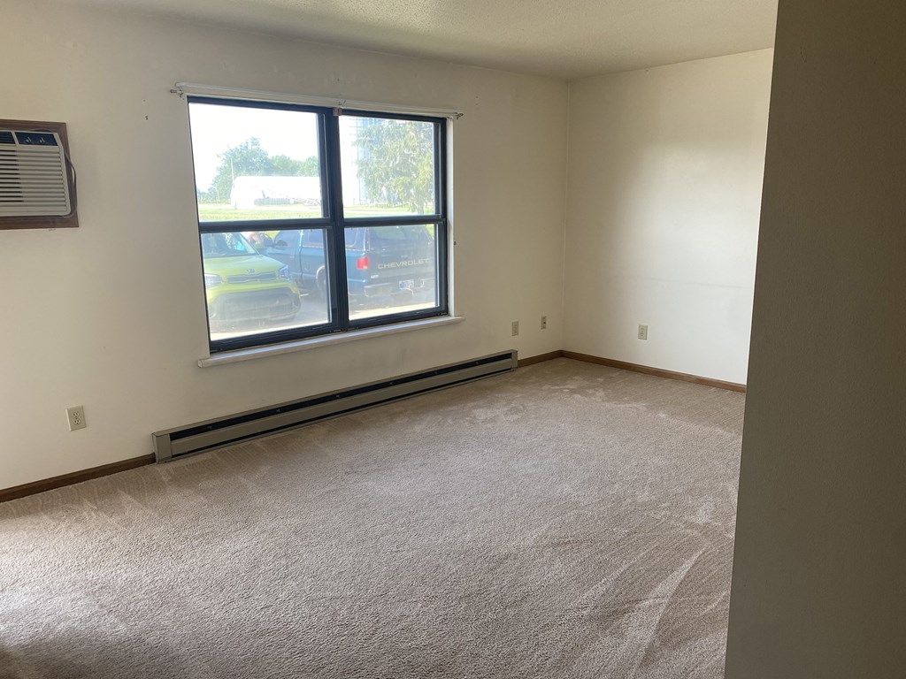 an empty room with a window and a carpeted floor