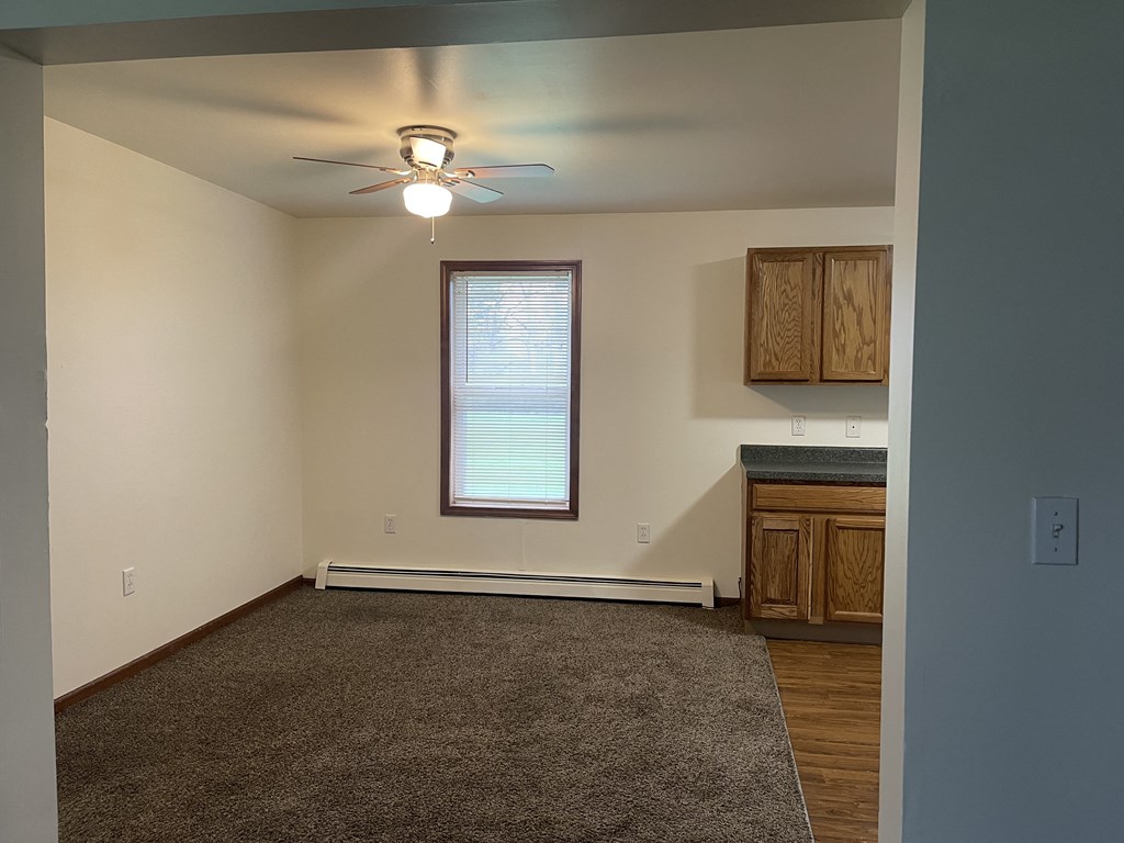 an empty living room with a ceiling fan and a window