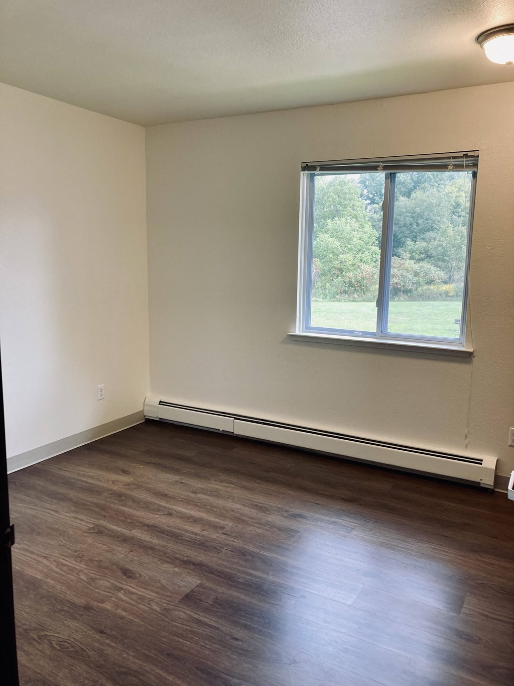 an empty room with wood floors and a window
