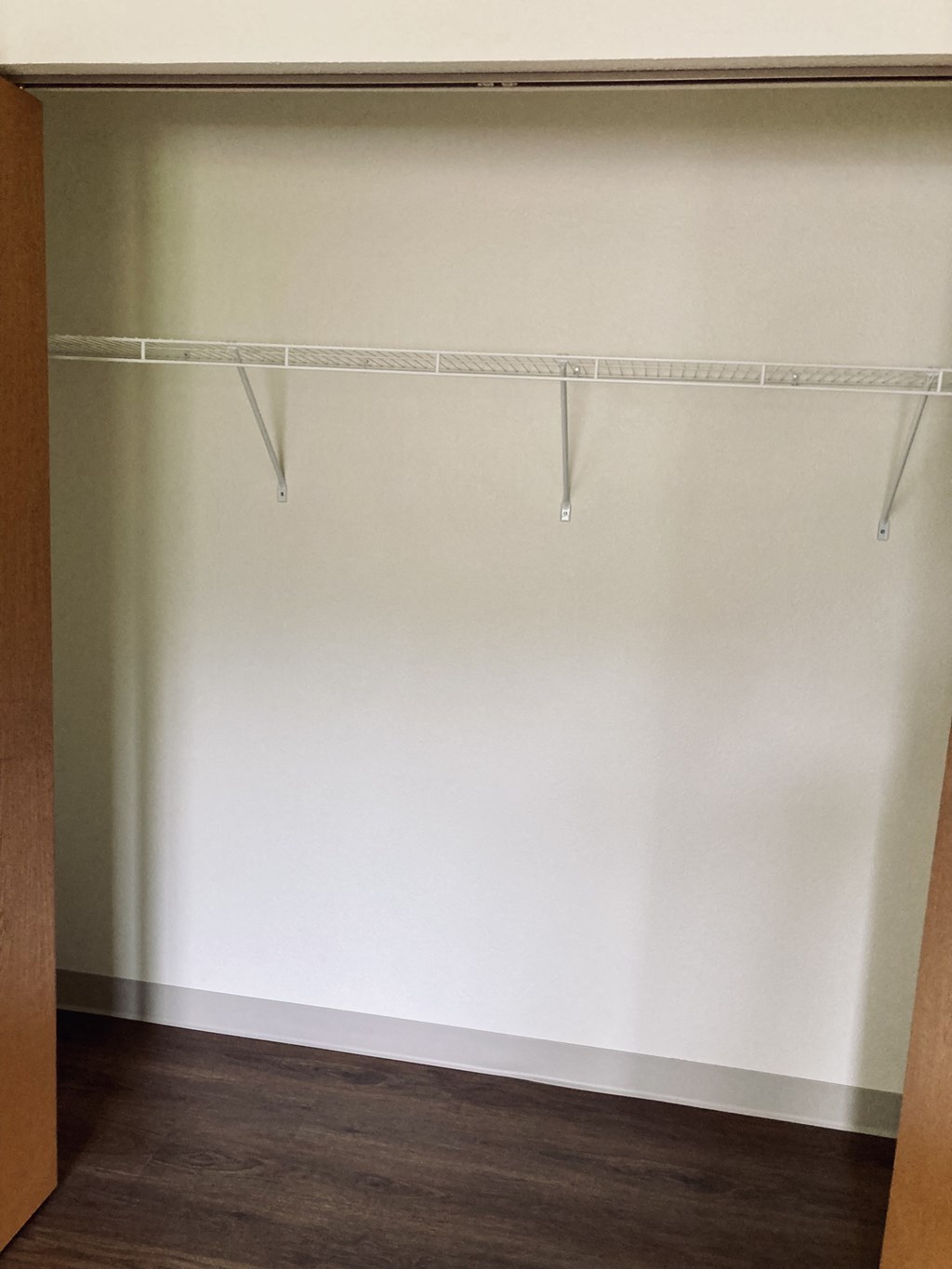 an empty closet with white walls and a wood floor