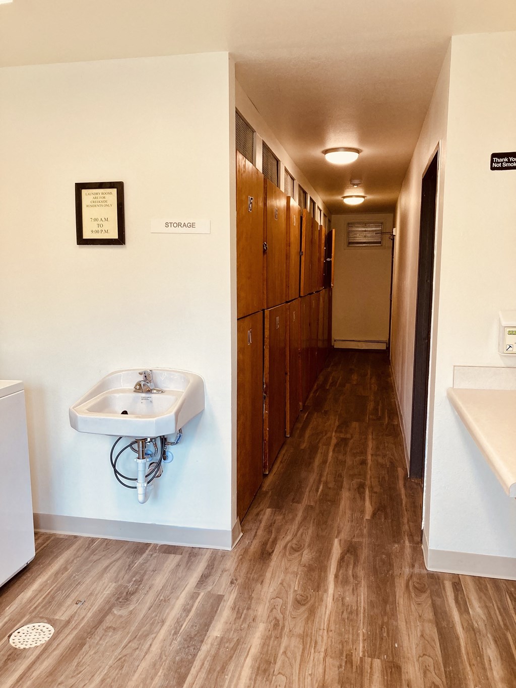 a bathroom with a sink and a long hallway with wooden floors