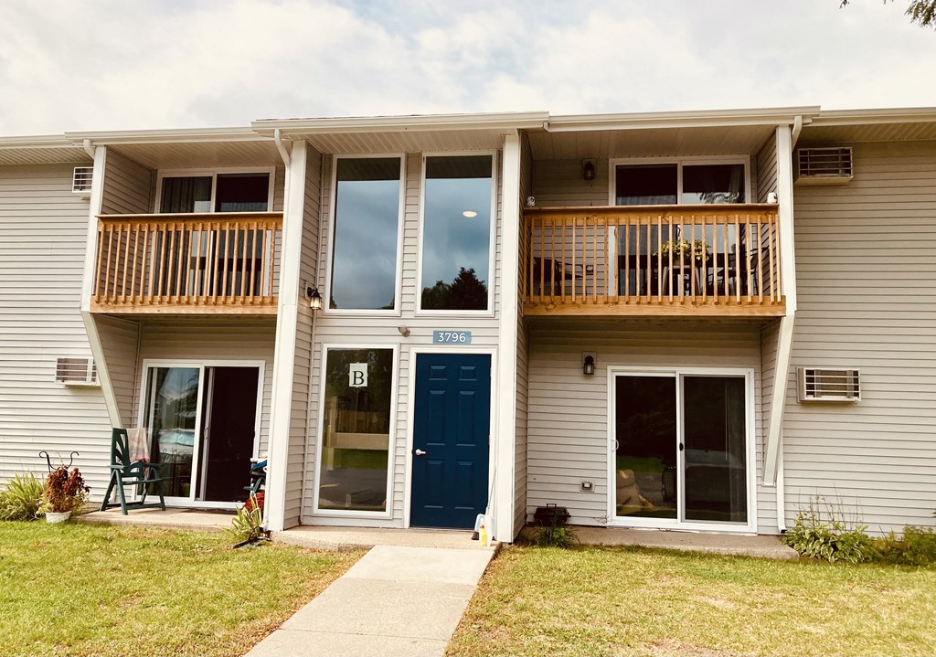 the front of a white house with a blue door