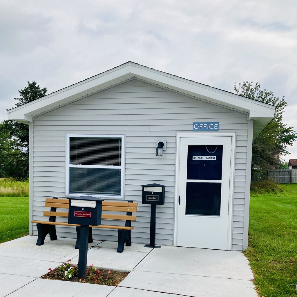 a small white building with a bench in front of it