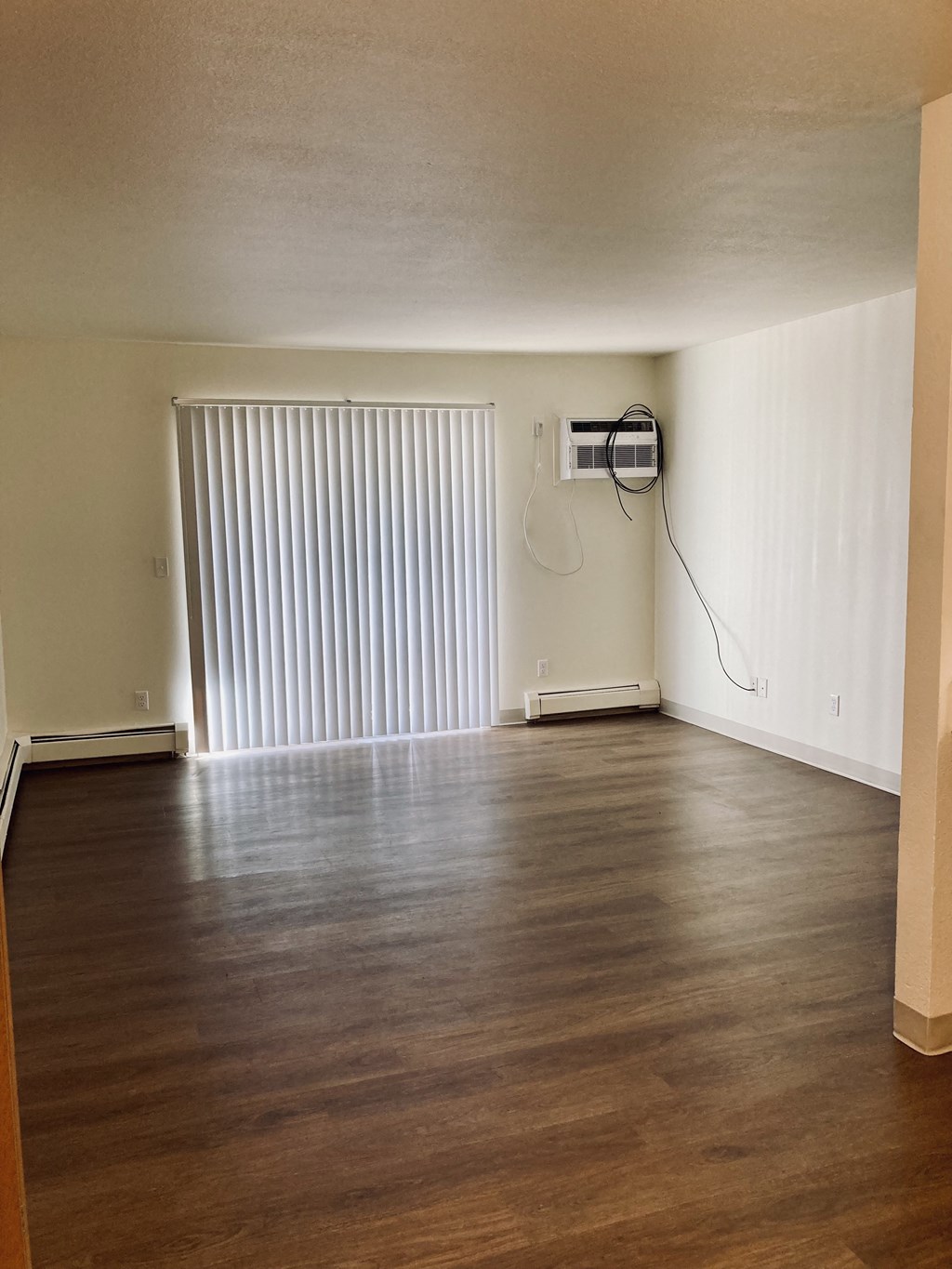 an empty living room with wood floors and a sliding glass door