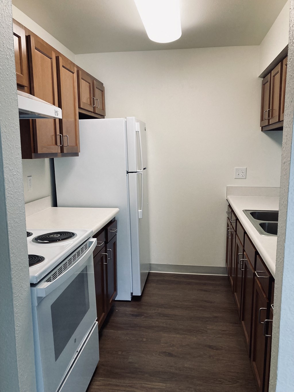 an empty kitchen with white appliances and wooden cabinets