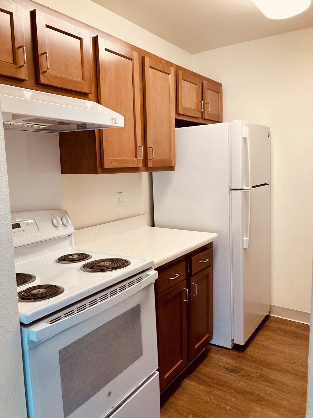 a kitchen with white appliances and wooden cabinets and a refrigerator