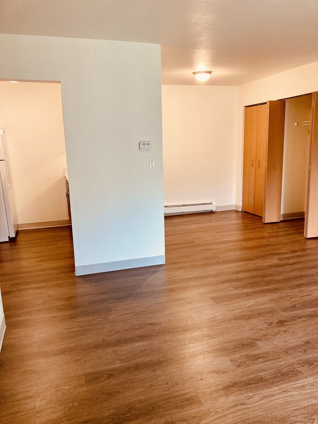 an empty living room with wood floors and a white wall