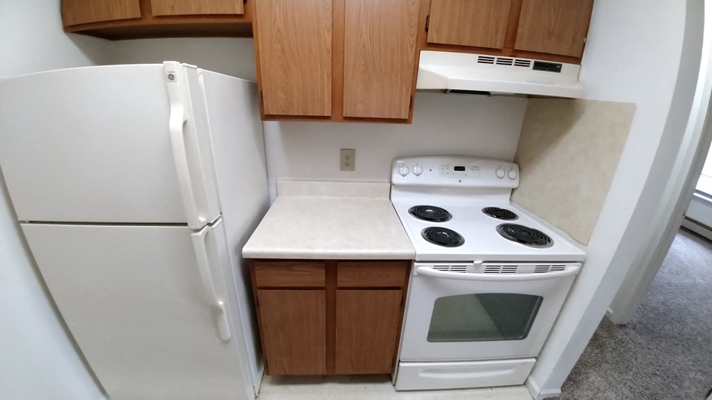 an rv kitchen with white appliances and brown cabinets