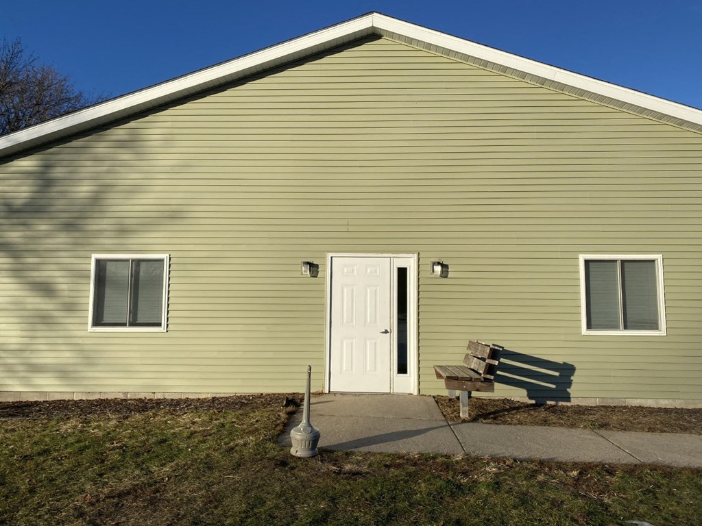 a wooden bench in front of a yellow building with a white door