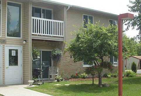 a house with a balcony and a tree in the yard