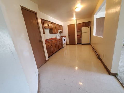 an empty kitchen with a white tile floor and wooden cabinets