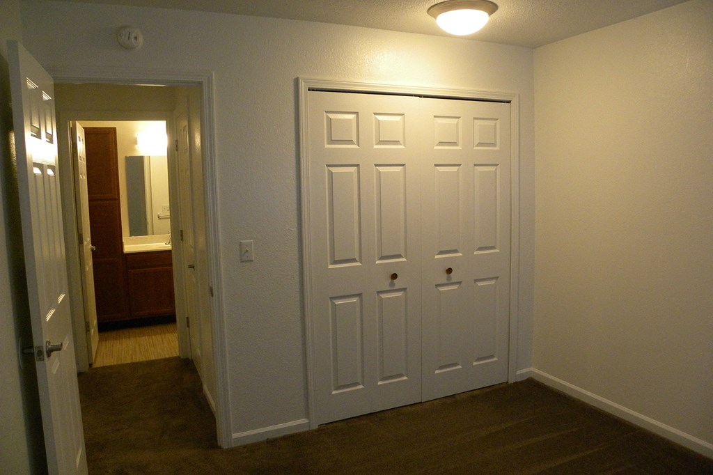 an empty room with a closet and a door to a bathroom