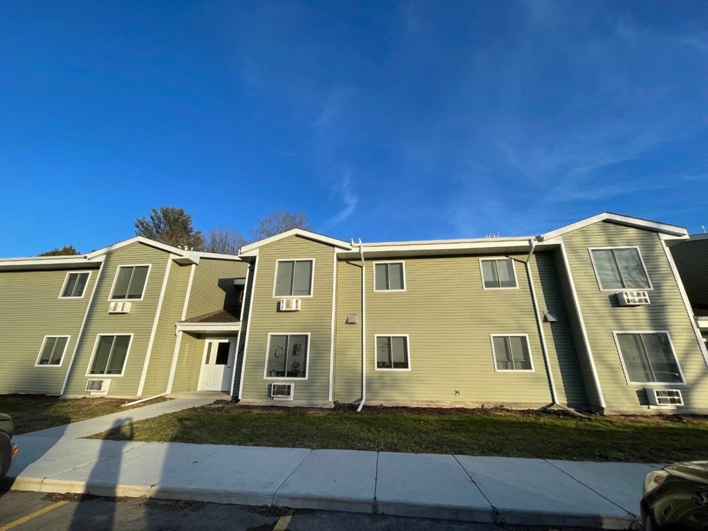 an apartment building with yellow siding and a blue sky
