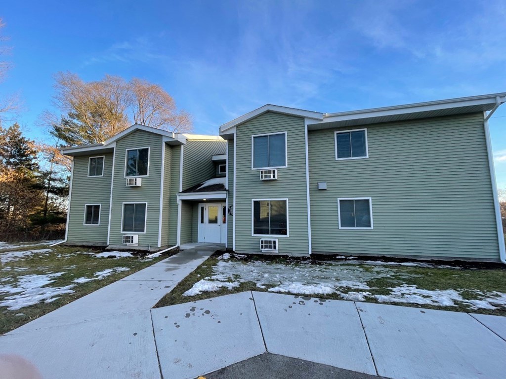the front of a green house with snow on the ground