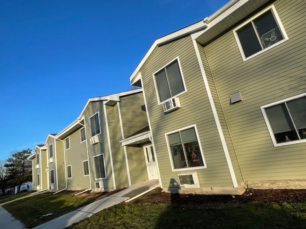 an apartment building with tan siding and a sidewalk