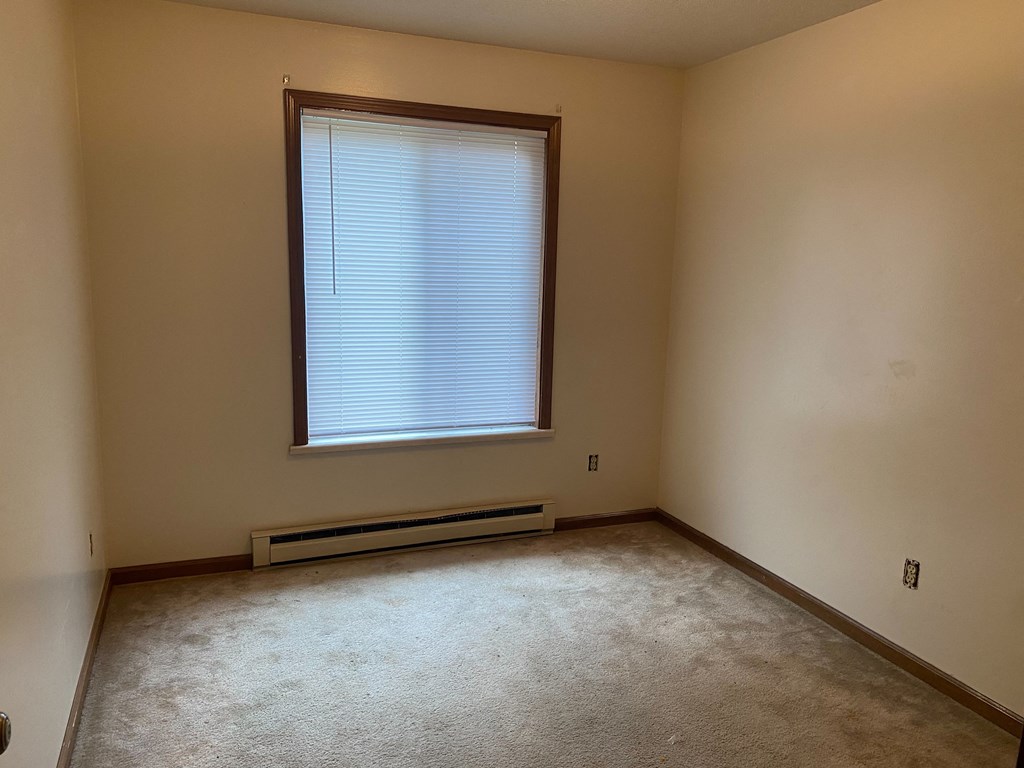 an empty room with a large window and a radiator