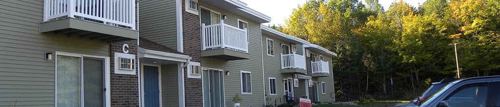 a row of apartments with balconies and cars parked in front