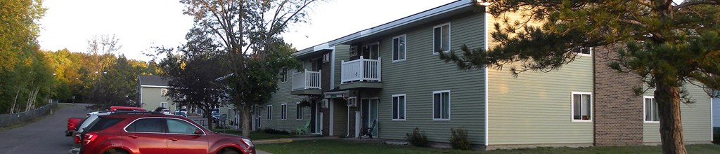 an apartment building with a red car parked in front