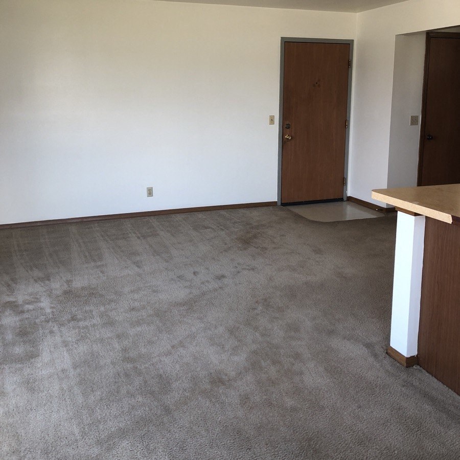 an empty room with a counter in the corner and a door in the background