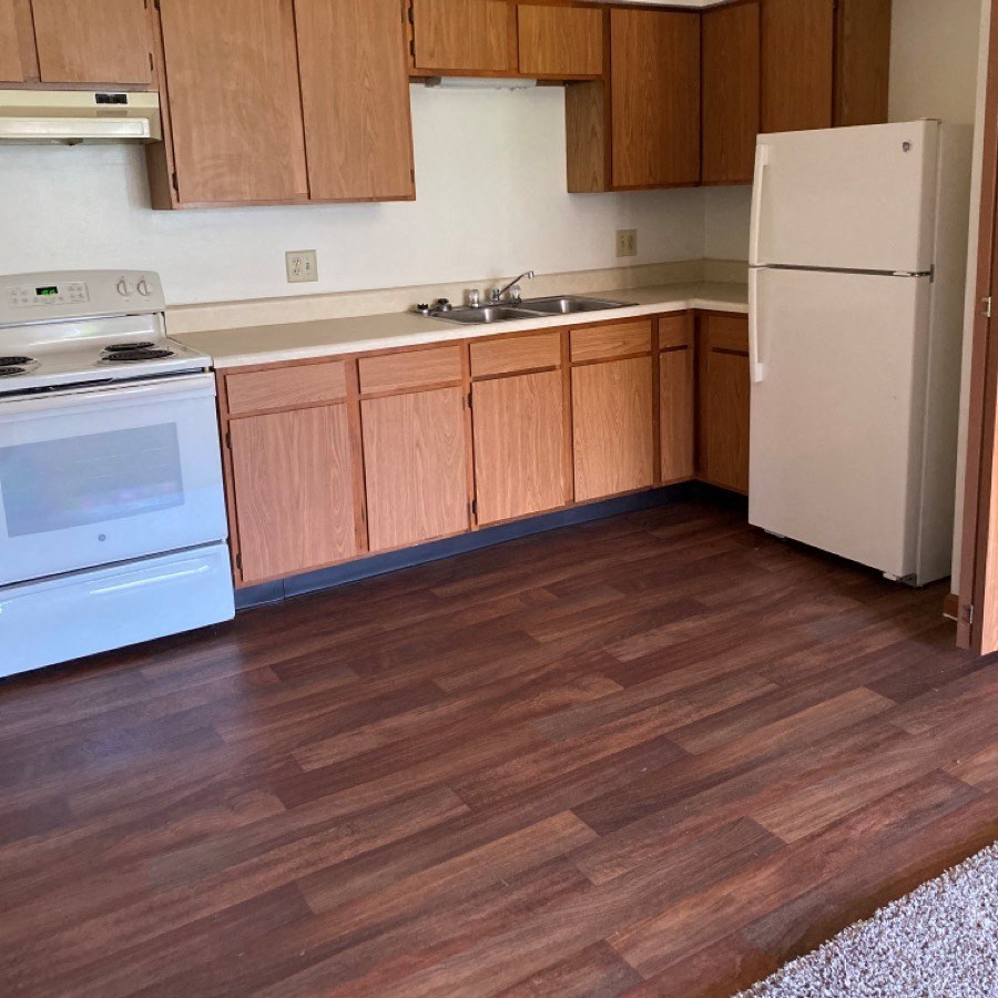 a kitchen with wood floors and white appliances