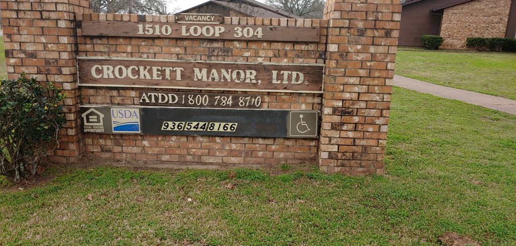 a sign for the crockett manor ld in front of a brick