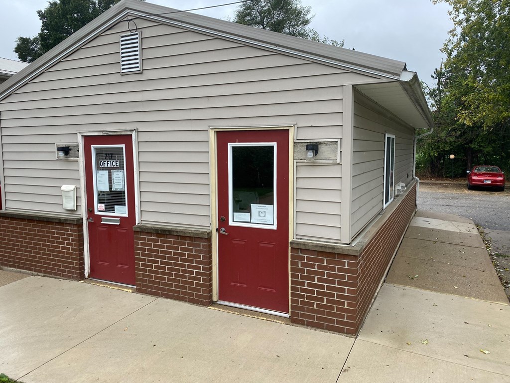 a small building with two red doors and a sidewalk in front of it